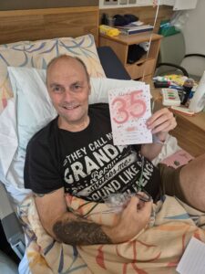James smiles while holding a '35th' anniversary card