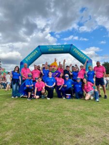 Group posing beneath a “You made a difference” finish-line arch at an outdoor event.