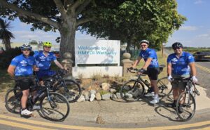Tour de hmp cyclists posing with location sign